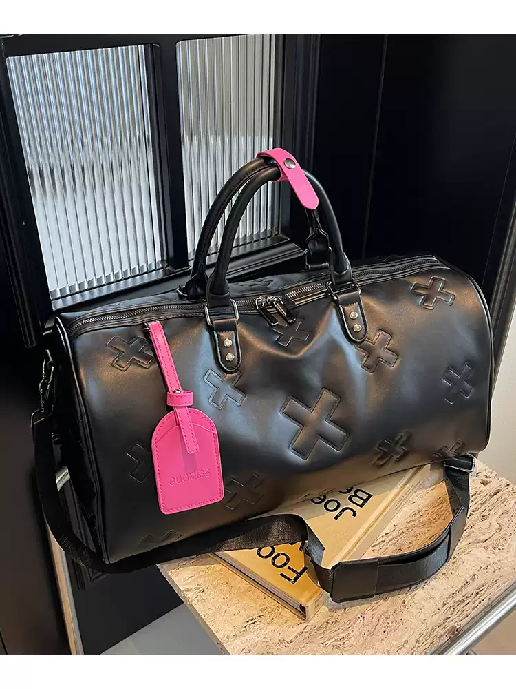 è Voyager embossed duffle bag in black with pink luggage tag