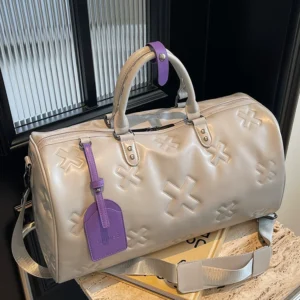 è Voyager embossed duffle bag in cream with purple luggage tag