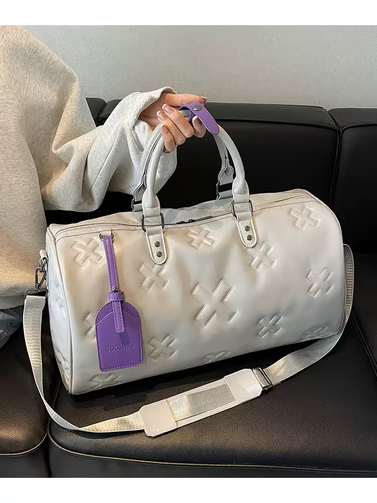 Woman holding the cream è Voyager duffle bag by its handles